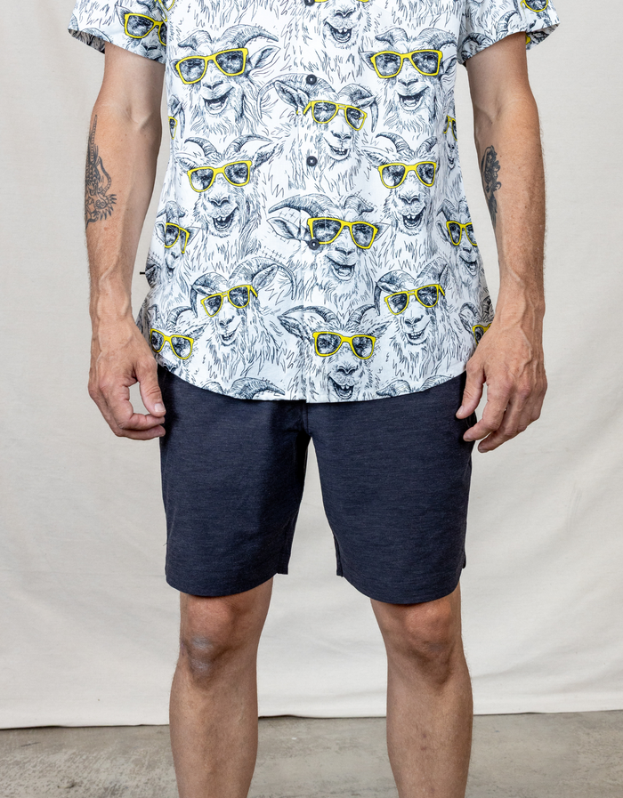 Front view of the Baja Llama Magellan Explorer Shorts in Black Heather, styled with a patterned goat-print button-down shirt for a casual adventure look.