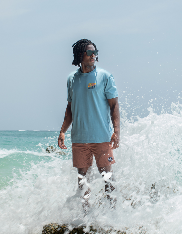 Ocean rock lifestyle of light blue Take A Hike Primo tee with sun chest logo