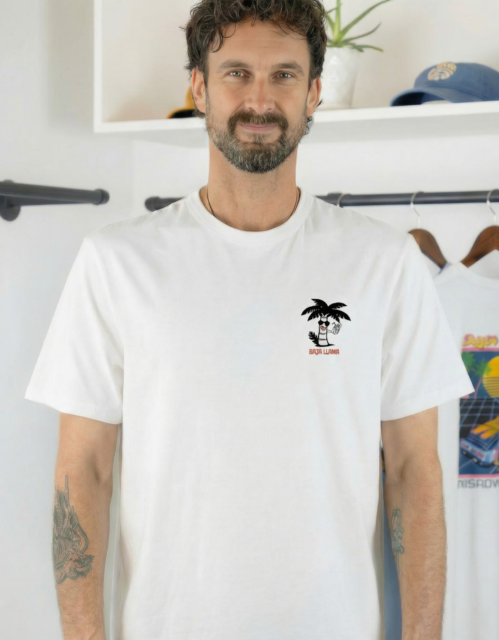 Man wearing a white Baja Llama "Enjoy The Trip" Primo Graphic Tee with a small palm tree chest logo.