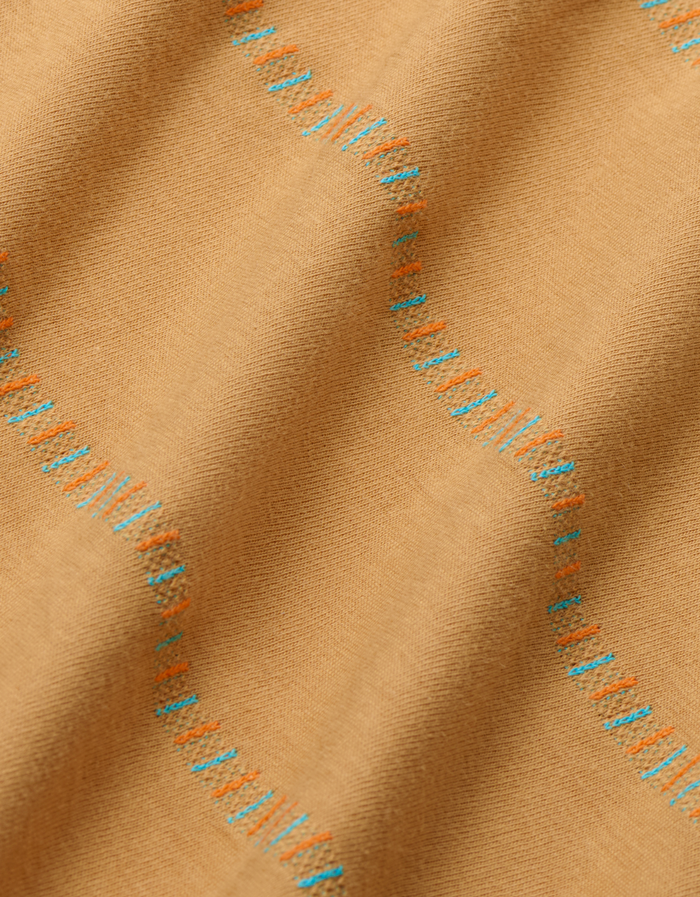 close up of a mustard yellow/camel t-shirt with blue pattern stripes