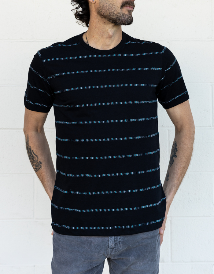 Man wearing a black and turquoise striped t-shirt on a white background