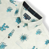 Tan button up shirt with various cactus print in turquoise