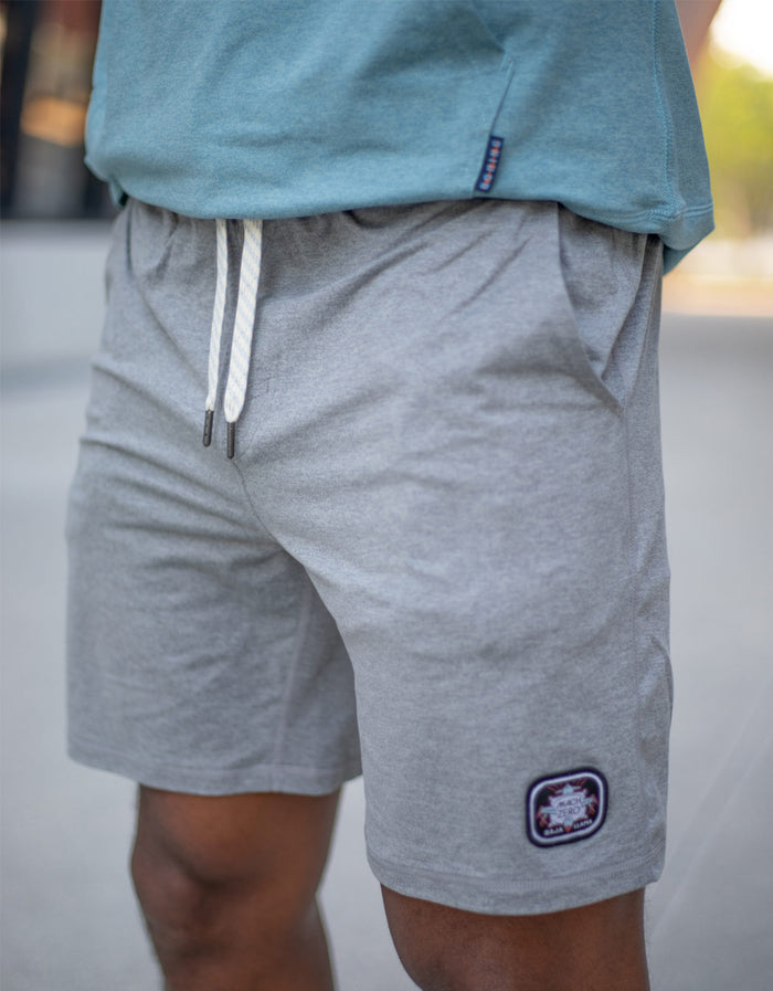 A model wearing the Baja Llama Mach Zero Lounge Shorts in gray, highlighting the elastic drawstring waistband and signature brand patch.