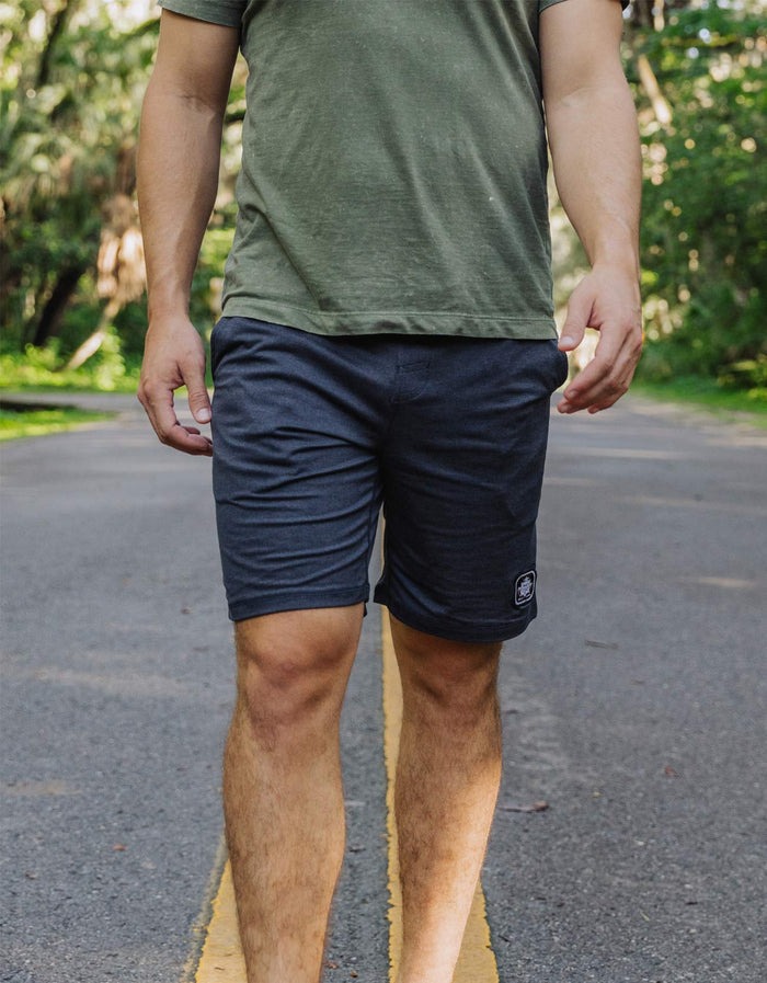A model walking outdoors wearing the Baja Llama Mach Zero Lounge Shorts in navy, featuring a comfortable athletic fit and branded patch.