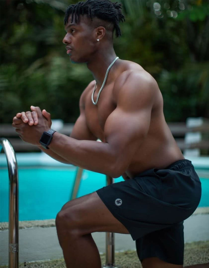 A model wearing Baja Llama Relaxplorations black athleisure shorts while exercising poolside, highlighting the flexible performance fit.