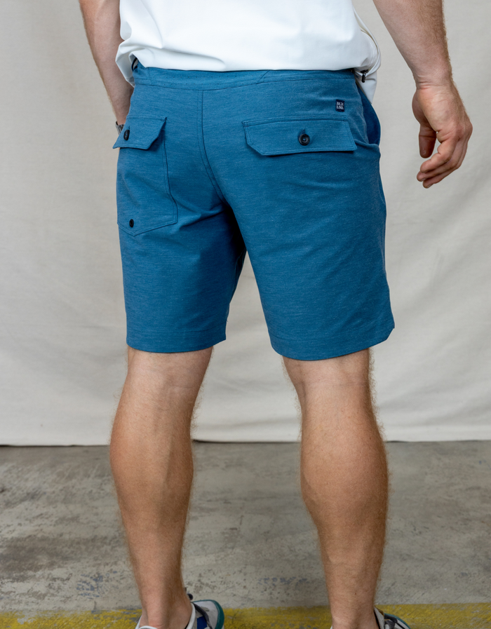 Back view of the Baja Llama Magellan Explorer Shorts in Mallard Blue, showing the buttoned back pockets and hybrid design.