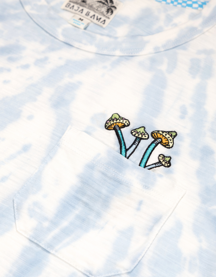Close-up view of the embroidered mushroom graphic on the pocket of the Baja Llama Trip of a Lifetime Slub Pima Pocket Tee, showcasing the blue tie-dye fabric.