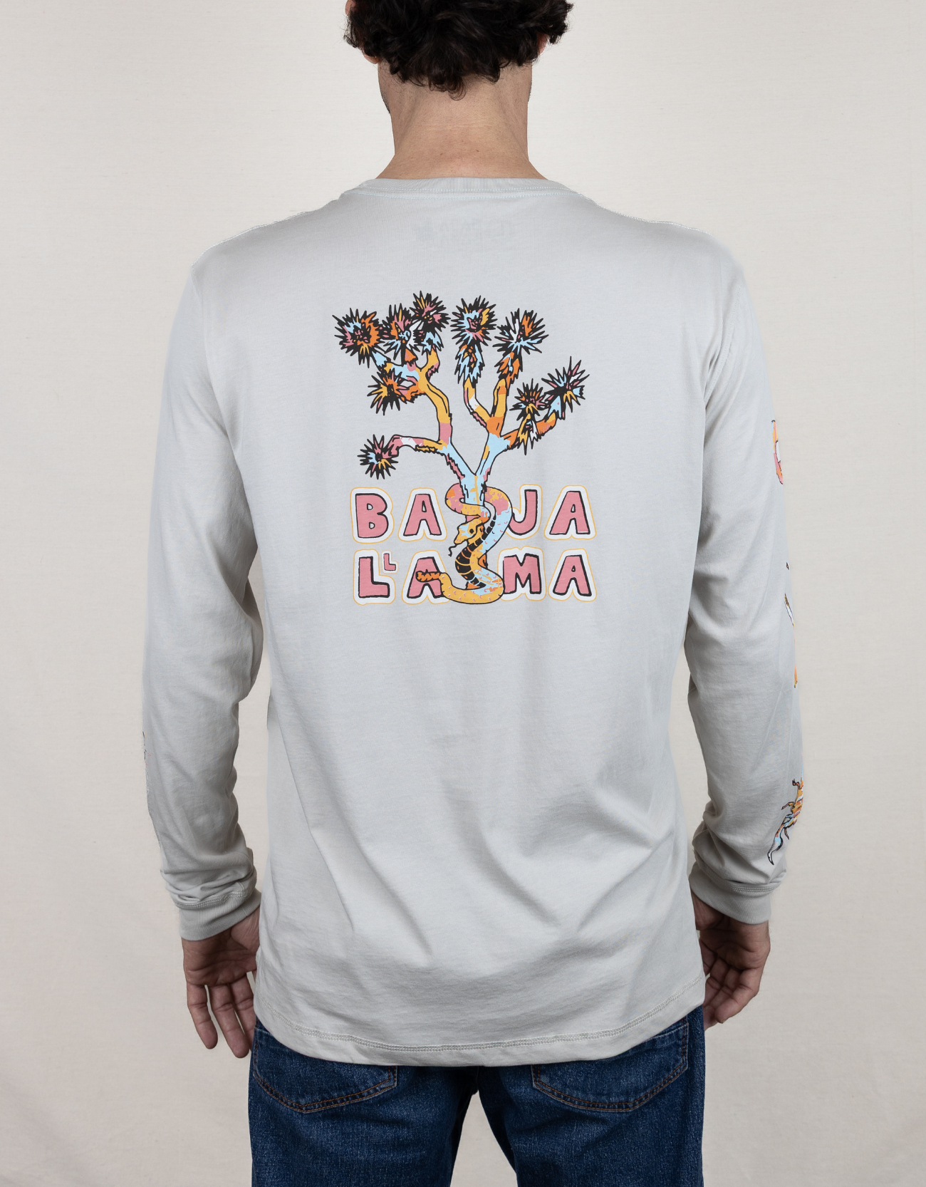 Baja Llama light desert-themed long sleeve tee with snake and Joshua tree back graphic. Soft cotton with printed sleeve details.