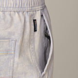 Acid wash gray cotton shorts with a brand label on a beige background