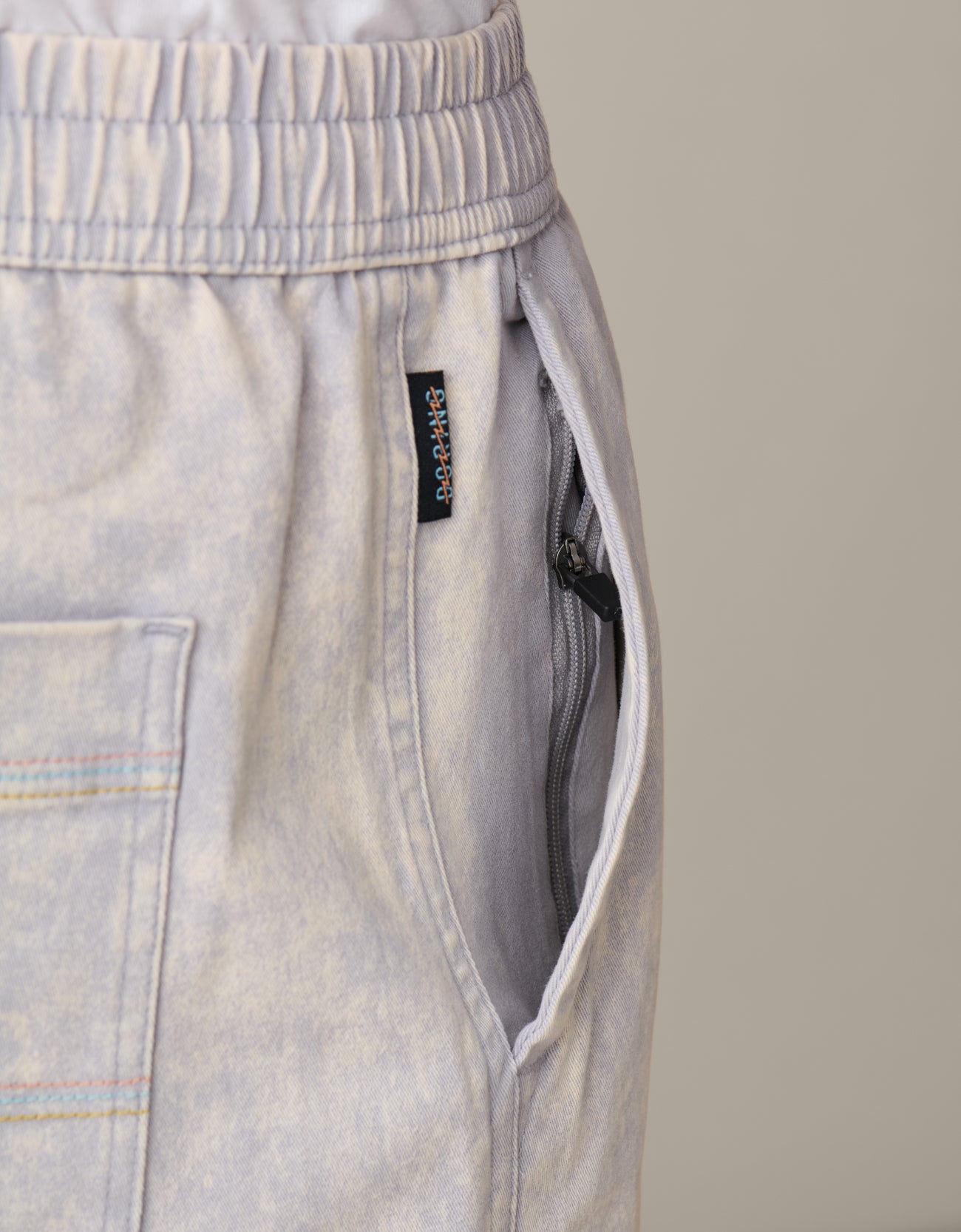 Acid wash gray cotton shorts with a brand label on a beige background