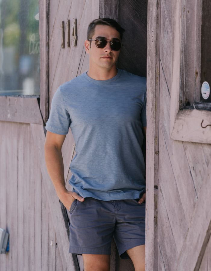 Man at door 114 wearing slate blue Solid Slub Pima tee with charcoal shorts