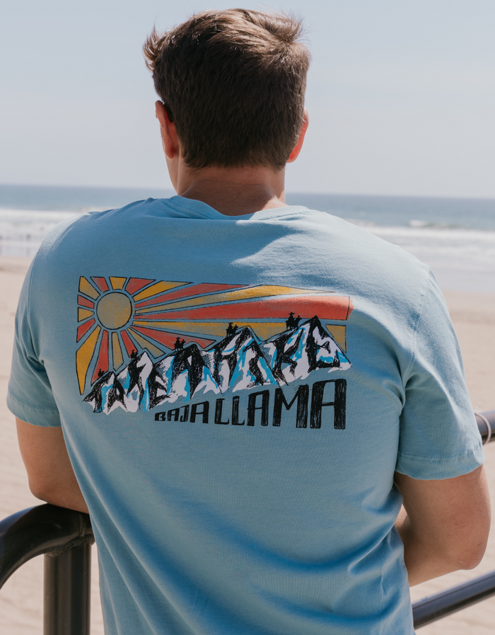 Beach overlook back view of light blue Take A Hike Primo tee with mountain TAKE A HIKE graphic