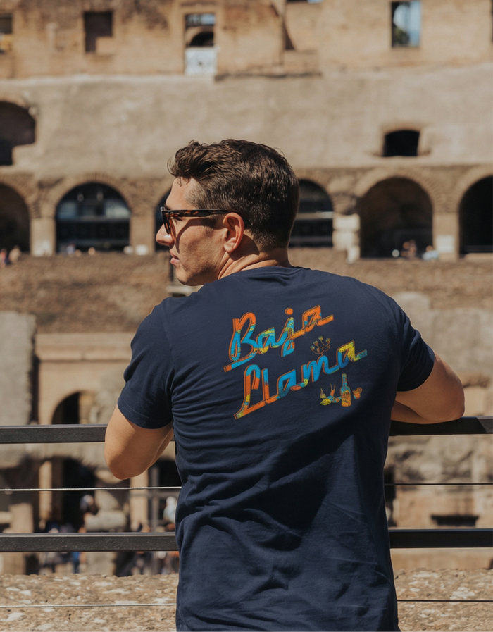 Back view of the Baja Llama El Sativo Primo Graphic Tee on a model in a travel setting.