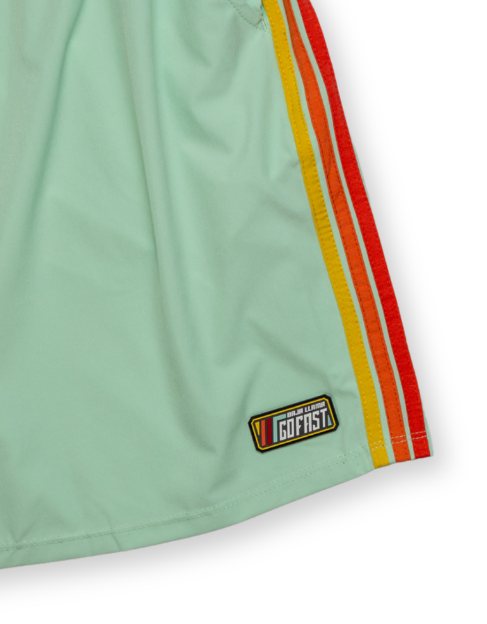 Close-up of the Baja Llama Relaxplorations Go Fast Ice Mint Athleisure Shorts, showing the mint green fabric, retro yellow, orange, and red side stripes, and a 'Go Fast' patch near the hem against a white background