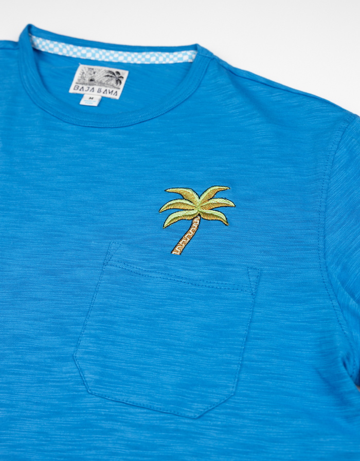Close-up of the blue Baja Llama Palm Tree Slub Pima Pocket Tee, featuring embroidered palm tree detail on the front chest pocket.