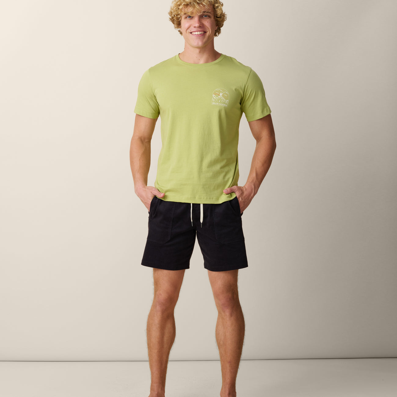 Man wearing Baja Llama Never High Enough Primo graphic tee in light green with mountain logo