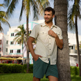 Man leaning against a palm tree wearing the Bee A Legend Dissident Western Front Snap Button Up by Baja Llama