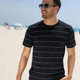 Lifestyle photo of a man wearing a black striped jacquard short-sleeve t-shirt outdoors near the ocean