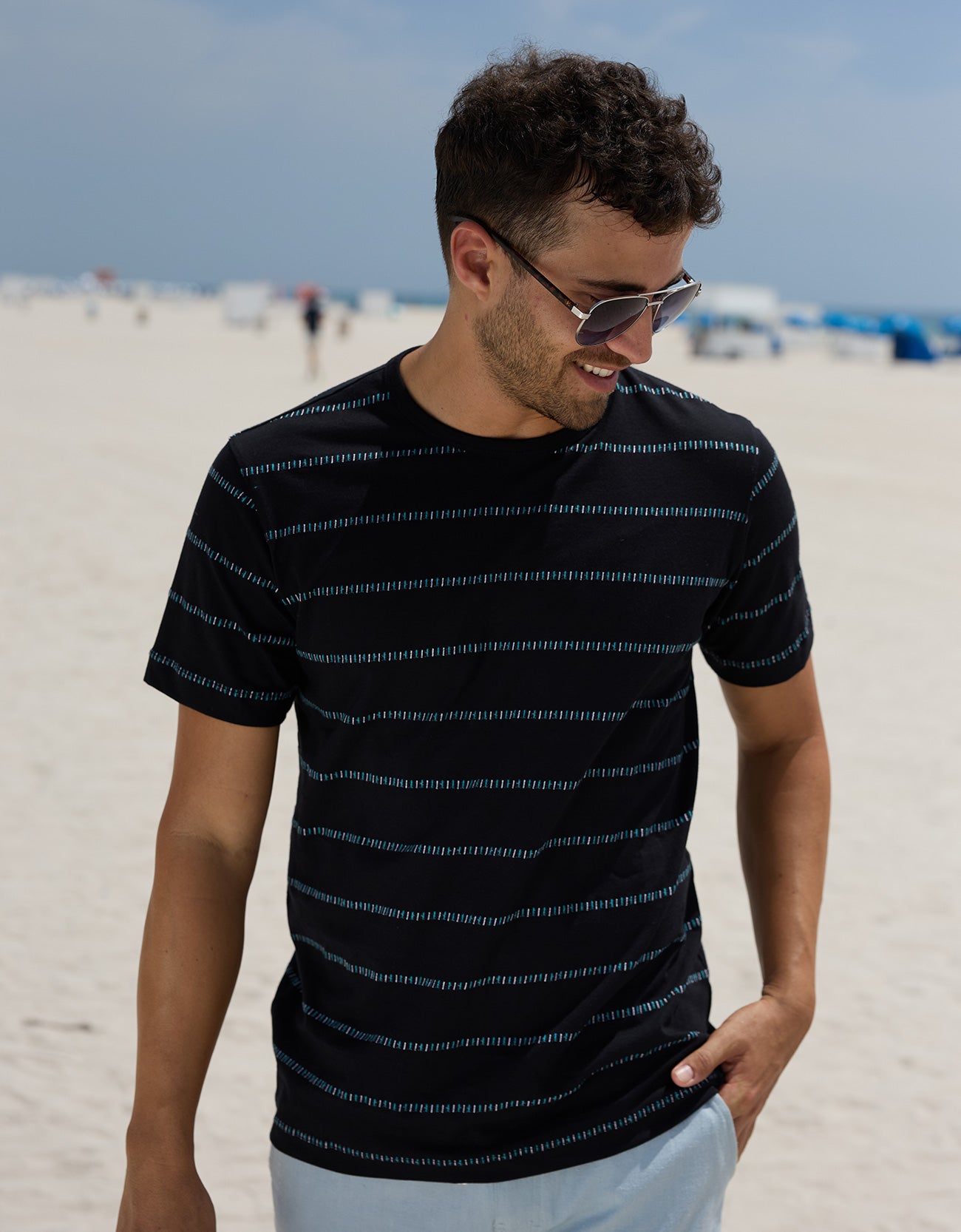 Man wearing the Baja Llama Black Onassis Jacquard Tee on a sunny beach