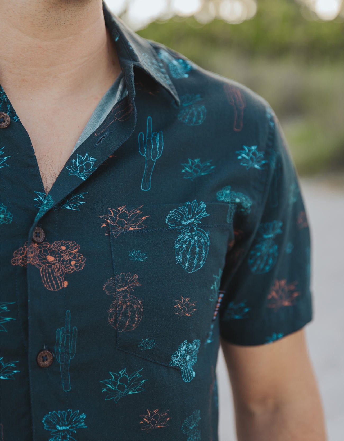 Black button up shirt with neon cactus print, side zipper pocket, branded buttons