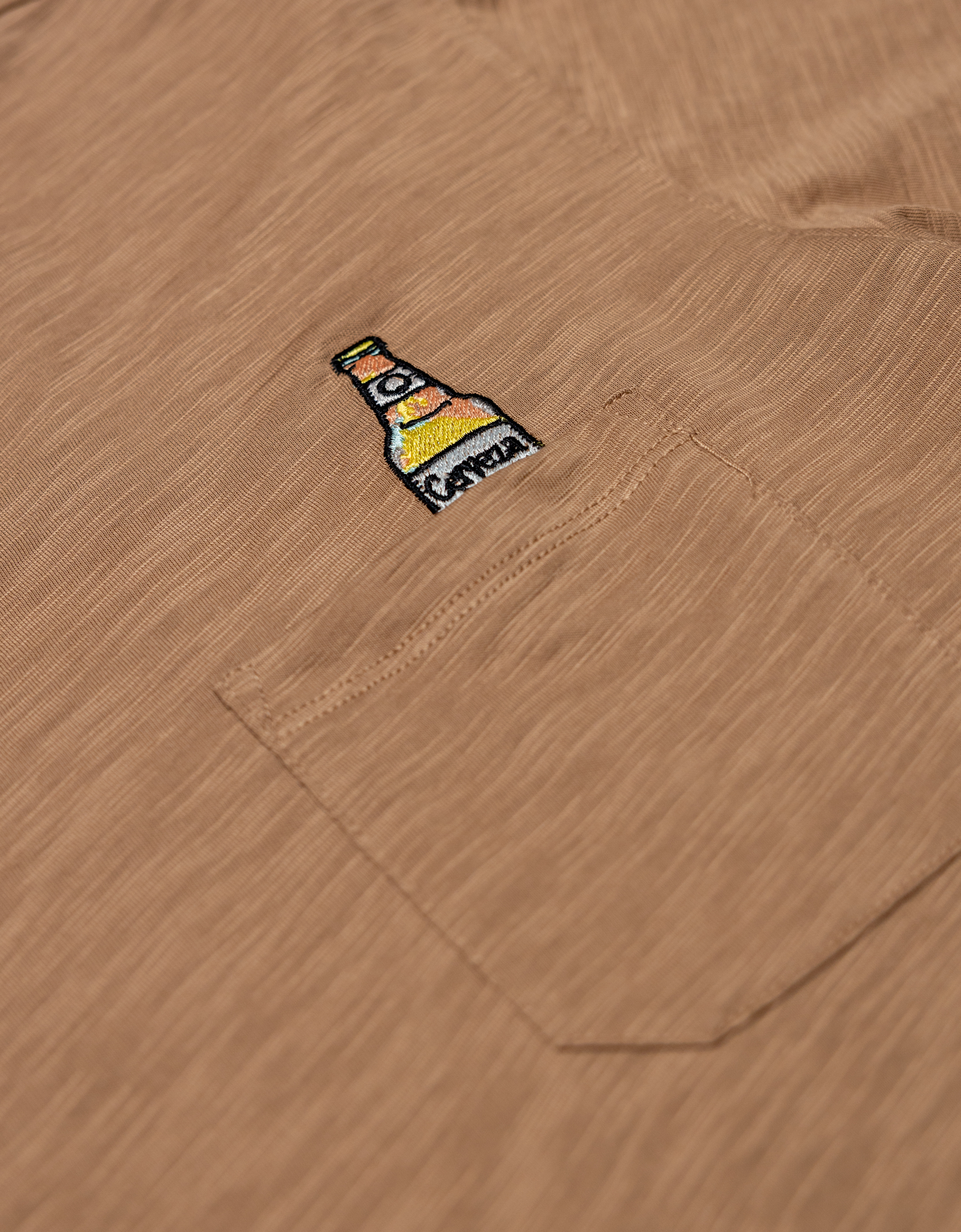 close up shot of the the beer embroidery logo on the shirt pocket.