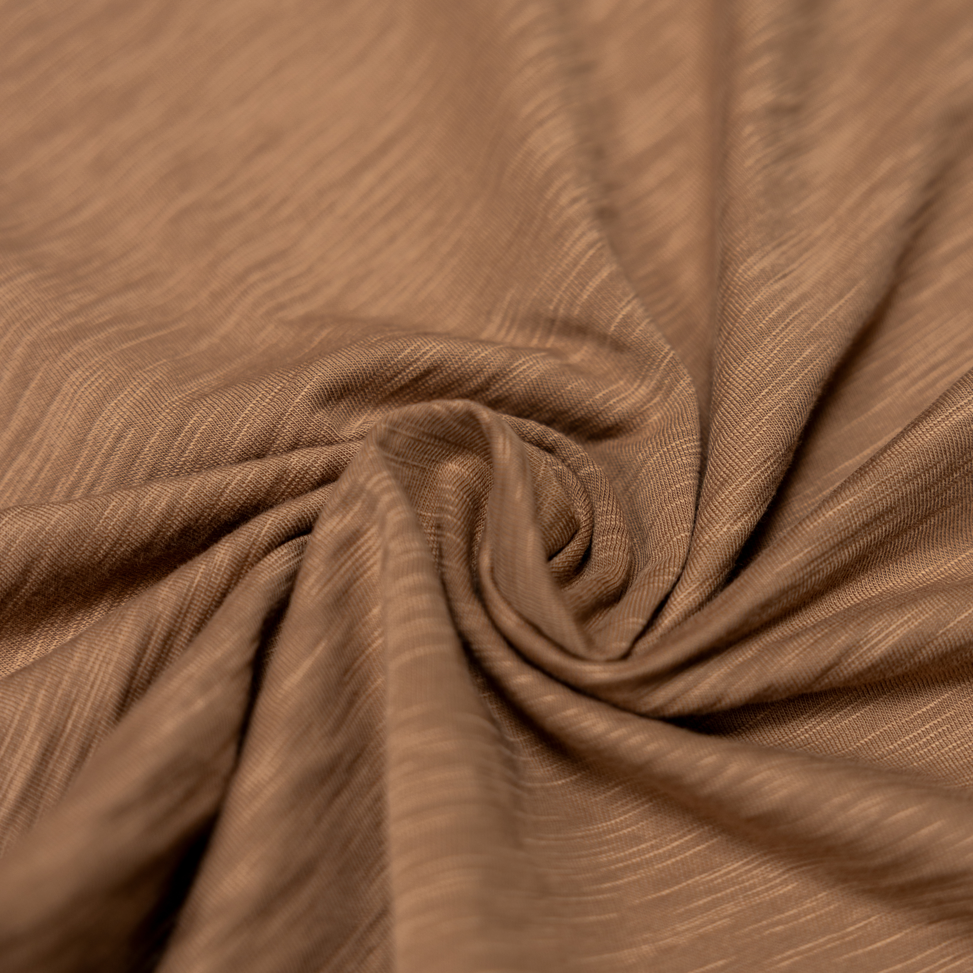 An extreme close-up  shot of the brown pima slub knit fabric from the Baja Llama La Republica Embroidered Pocket Tee, showing the highly textured, slub cotton gathered into a soft swirl.