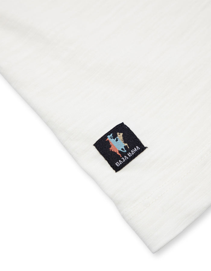 Hem Baja Llama tag close-up on cream Solid Slub Pima pocket tee