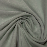 A close-up view of the Baja Llama Greatful Dyed Rock On Cypress Green Heavy Tee fabric, tightly swirled to display the heavy cotton texture and vintage-wash olive green color.