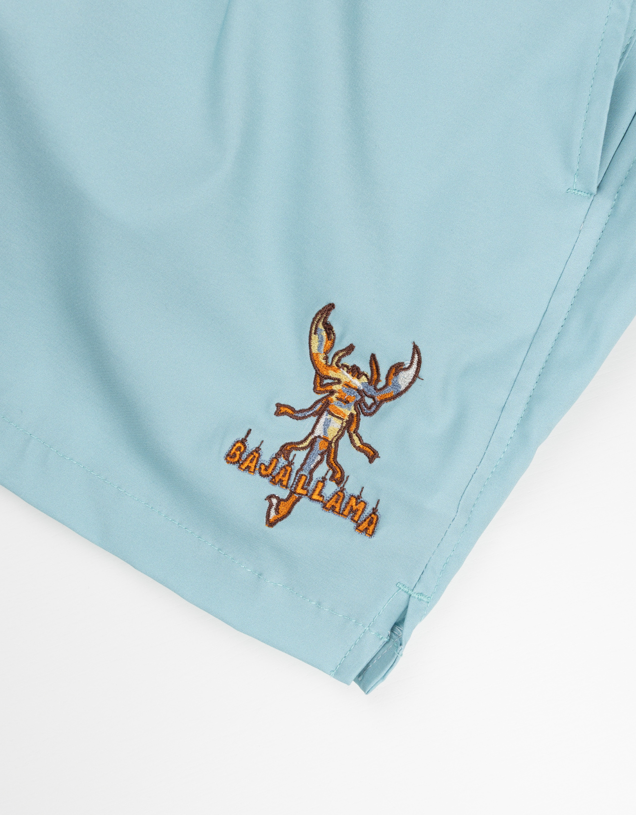 Men’s light blue swim shorts with retro-style orange and white side stripes, black elastic waistband, and adjustable drawstring. Features embroidered Baja Llama scorpion design and quick-dry fabric for all-day comfort.