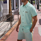 Man wearing the Baja Llama Go Fast Green Vagabond Button Up and matching shorts while walking outdoors.