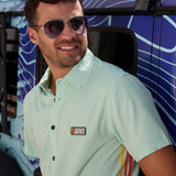Baja Llama Go Fast Green Vagabond Button Up shirt worn by a man wearing sunglasses next to a vehicle