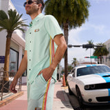 Man wearing the Baja Llama Go Fast Green Vagabond Button Up shirt and matching shorts outdoors by a sports car