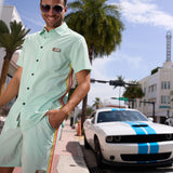 Baja Llama Go Fast - Green Vagabond Button Up shirt and shorts full outfit view next to a sports car