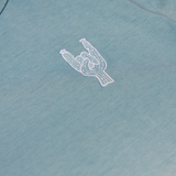 Close-up of the left chest on the Baja Llama Rock On Cactus Embroidered Primo S.E. Heavy Tee, showcasing the small white embroidered rock-on sign cactus against the teal-blue upper section of the shirt.