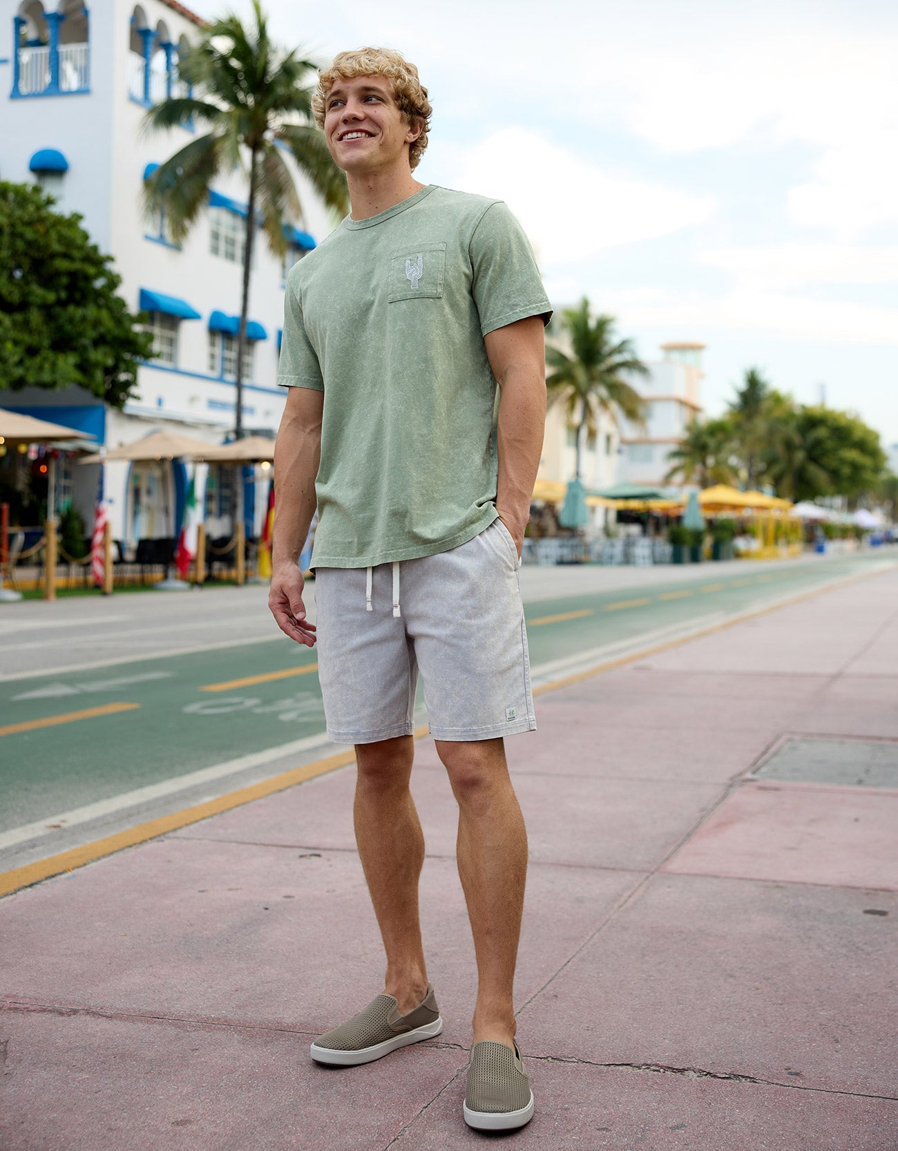 Man walking down a sunny street wearing the Baja Llama Greatful Dyed - Rock On Cypress Green Heavy Tee