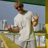 Man flashing hand signs on a lifeguard tower wearing the Baja Llama Greatful Dyed - Shoreline Smoke Heavy Tee