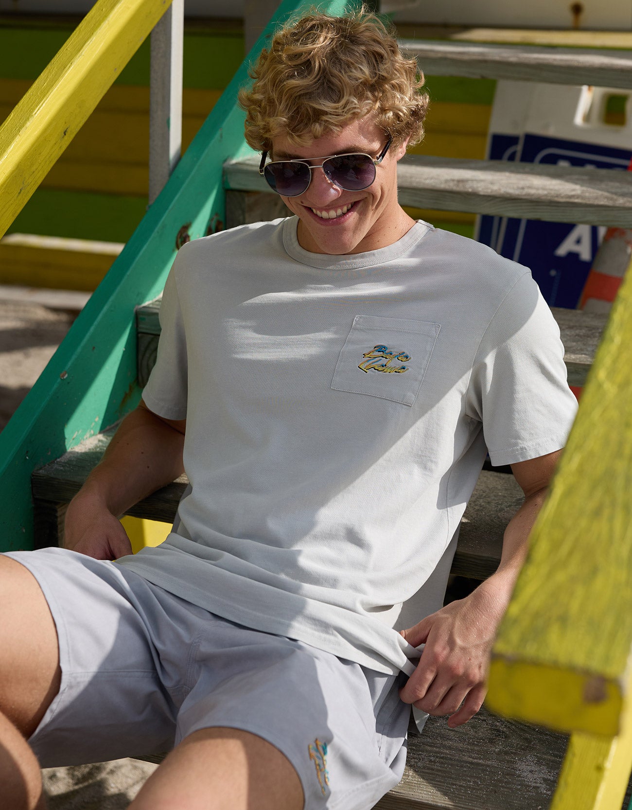 Man sitting on wooden steps wearing the Baja Llama Greatful Dyed - Shoreline Smoke Heavy Tee