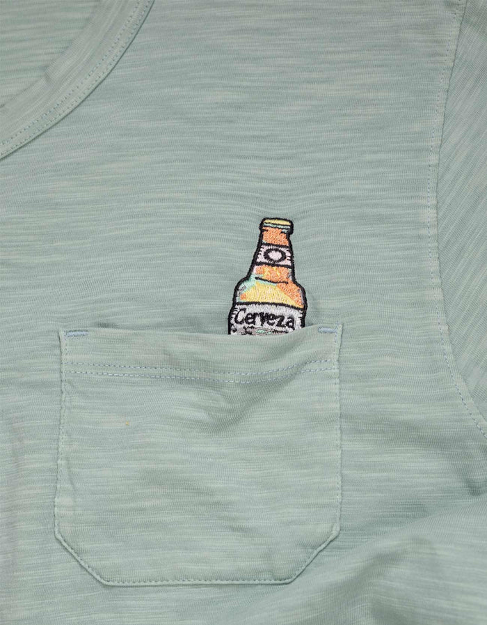 Close-up of the green Baja Llama Cerveza Slub Pima Pocket Tee, featuring detailed embroidered beer bottle artwork peeking out of the chest pocket.