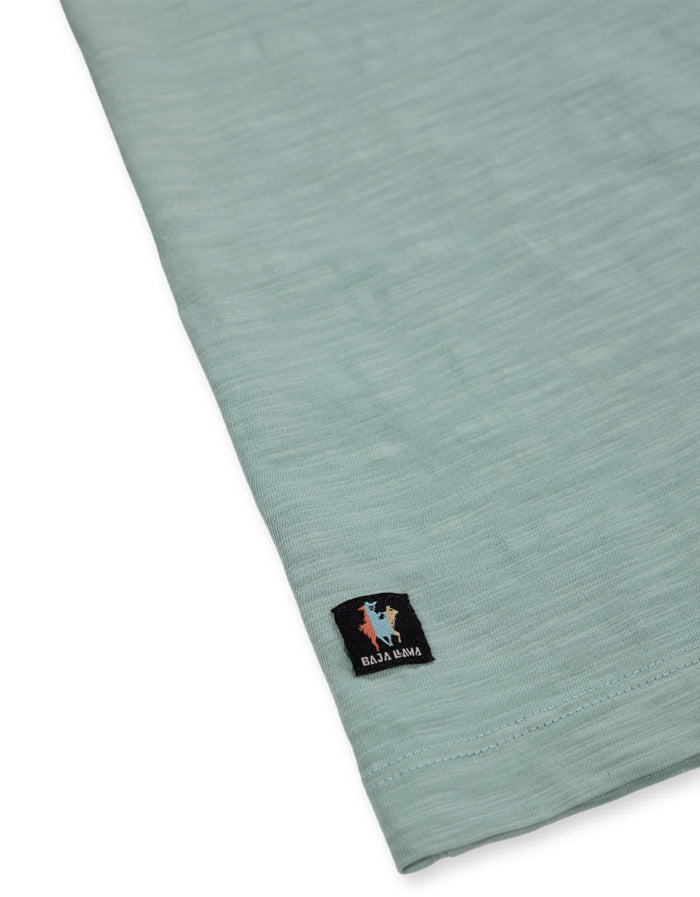 Hem llama tag close-up on sage Solid Green Slub Pima tee