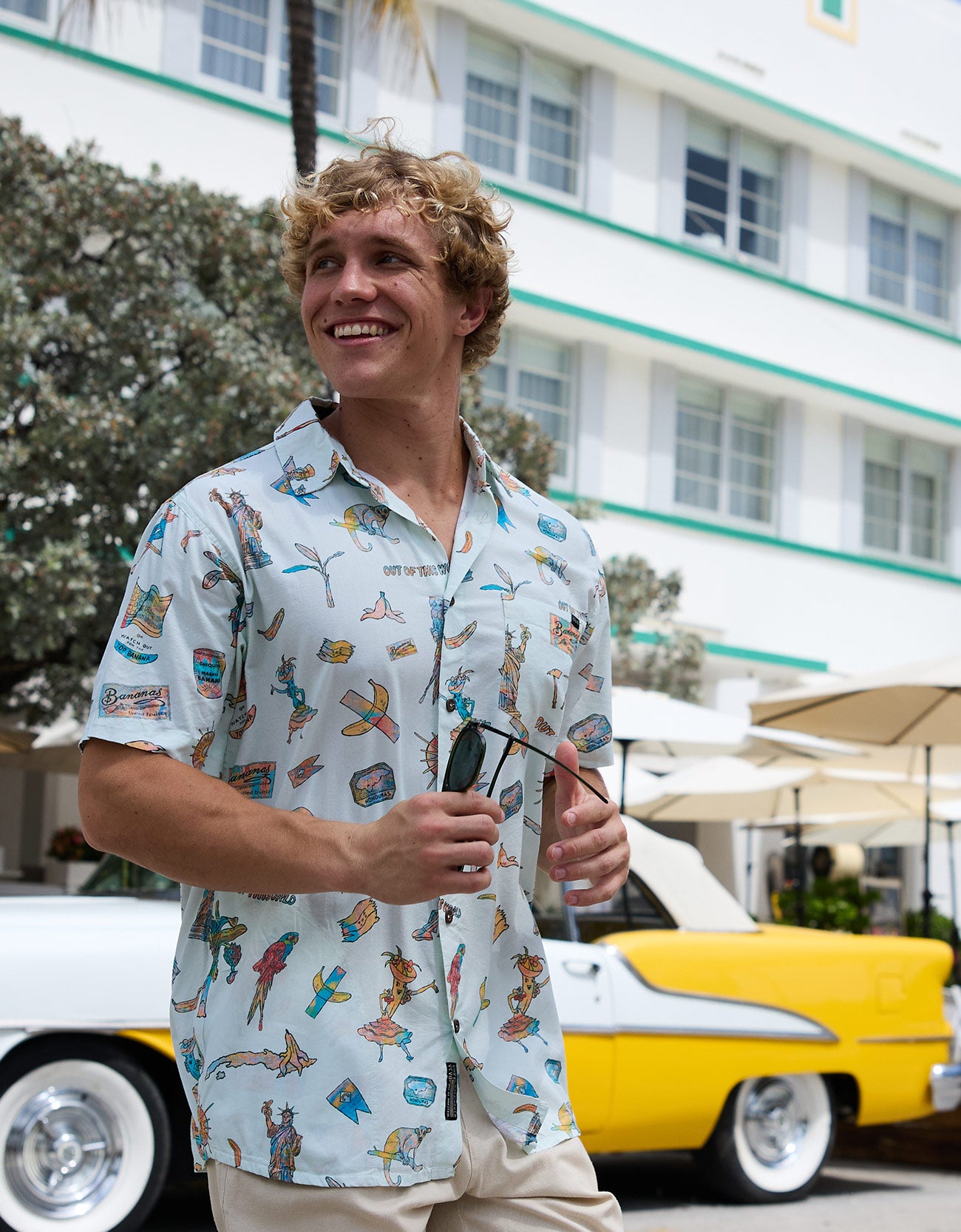 Model wearing the La Republica Bananera Icy Mint 7-Seas Relaxed Fit Button Up shirt by Baja Llama outdoors with vintage car