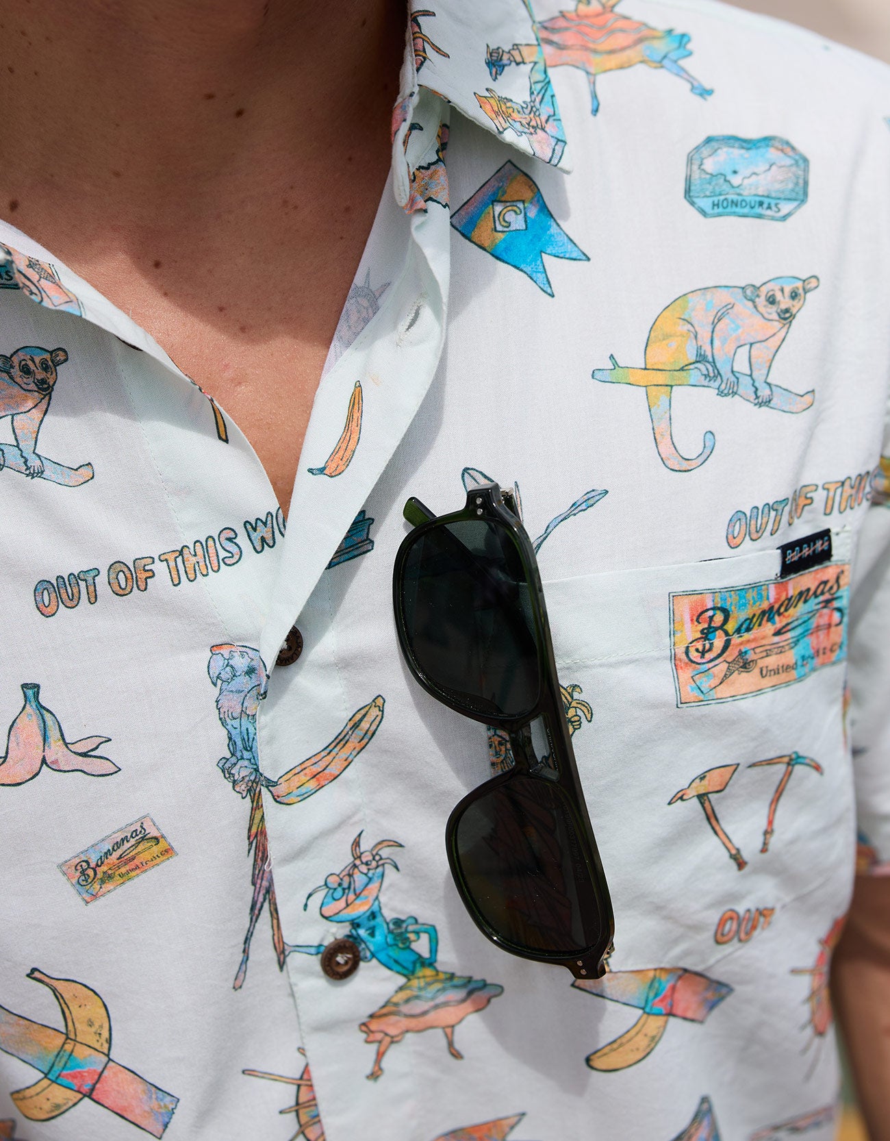Close-up of Baja Llama La Republica Bananera Icy Mint 7-Seas Relaxed Fit Button Up shirt showing pattern and sunglasses tucked into chest pocket