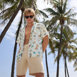 Man wearing Baja Llama La Republica Bananera Icy Mint 7-Seas Relaxed Fit Button Up shirt under palm trees