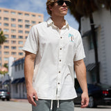 Model walking outdoors wearing Baja Llama La Republica Embroidery 7-Seas Relaxed Fit Button Up with palm tree embroidery and sunglasses