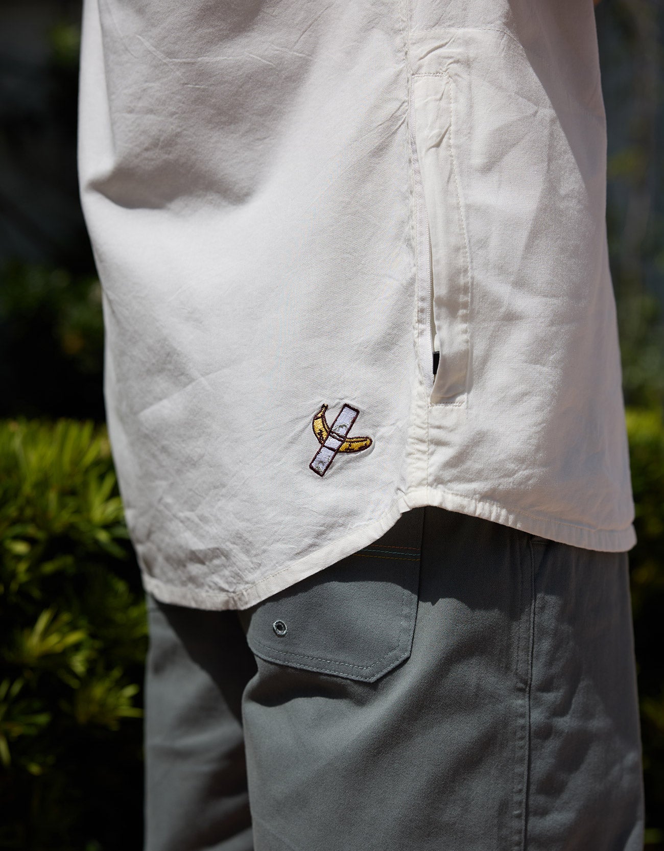 Close-up of white 7-Seas button-up shirt featuring custom hem embroidery and side pocket detail by Baja Llama