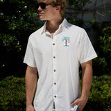 Model wearing white short-sleeve 7-Seas relaxed fit button-up shirt with chest embroidery and sunglasses outdoors