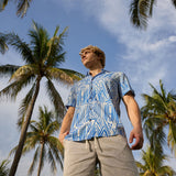 Man wearing Baja Llama Too Easys Acid Washed Gray Stretch Cotton Shorts and blue patterned button-up shirt under palm trees.