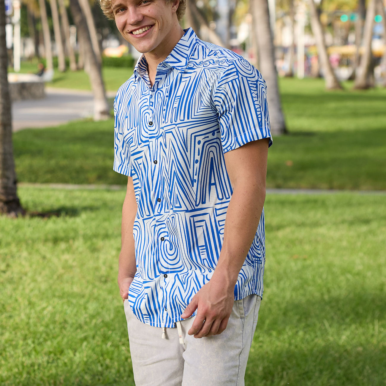 Model wearing blue and white geometric Line Work Mojave perforated short-sleeve button-up shirt in a park setting