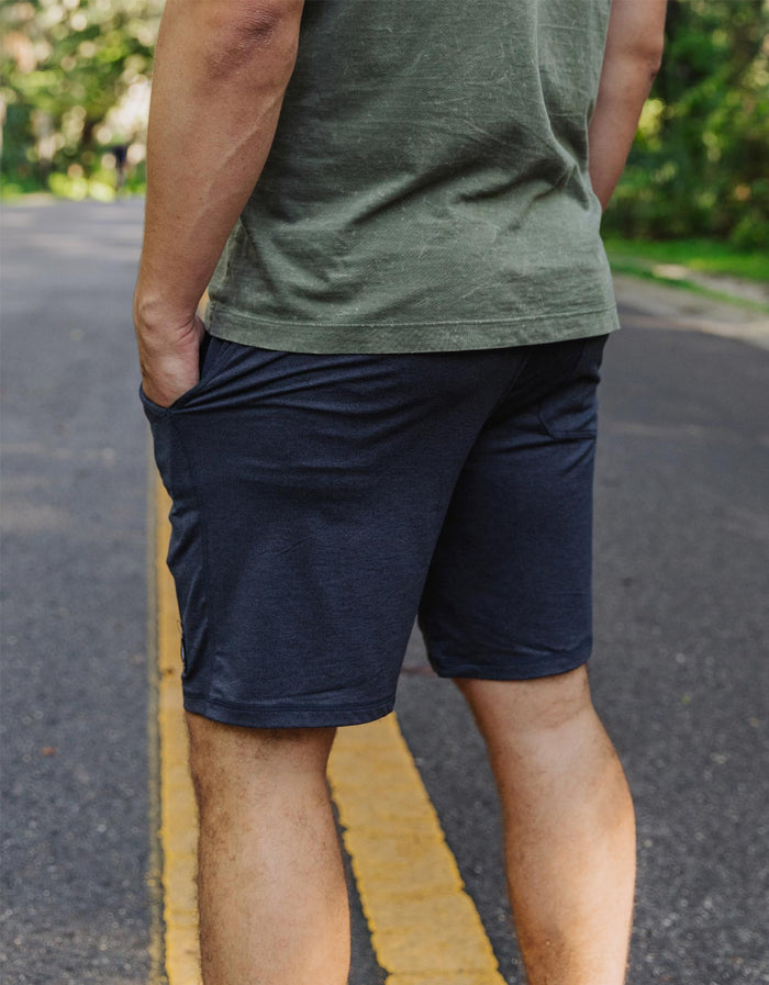 Rear view of a model walking outdoors wearing the Baja Llama Mach Zero Lounge Shorts in navy, highlighting the comfortable fit and side pocket detail.