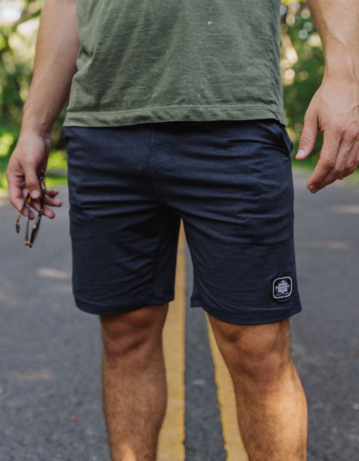A model wearing the Baja Llama Mach Zero Lounge Shorts in navy, featuring a comfortable fit and signature brand patch, captured in an outdoor setting.