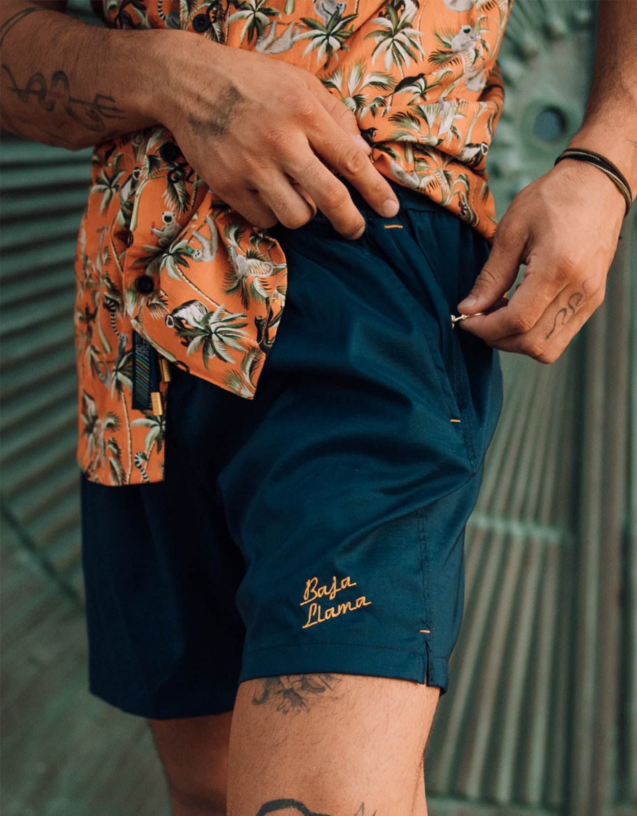 Solid navy men's swimsuit featuring embroidered "Taking Care of Business" slogan and Baja Llama logo.